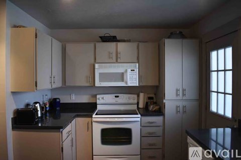 A kitchen with a white microwave oven mounted above a stove.