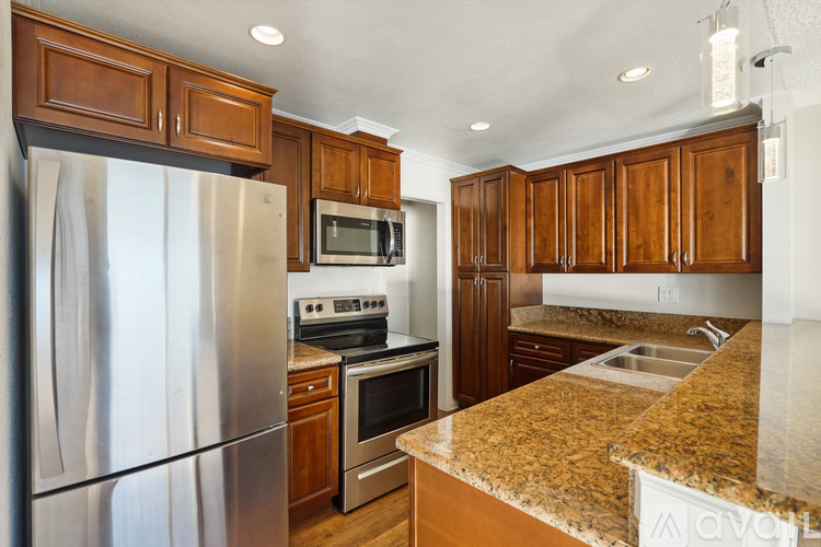 A kitchen with a granite counter top and stainless steel appliances.