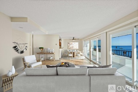 A living room with a grey couch and a view of the sea.