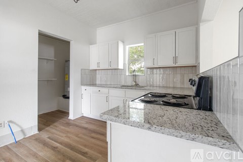 A kitchen with white cabinets and a granite countertop.