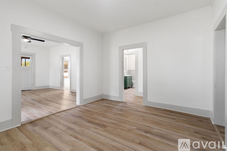 A spacious room with wooden flooring and white walls.