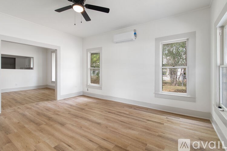 A room with a ceiling fan and a window with a view of trees.