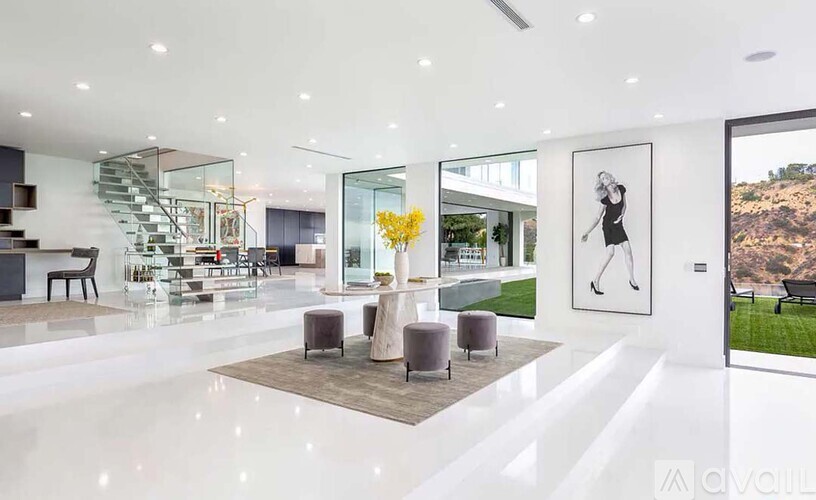 A modern living room with a staircase and a painting of a tennis player.