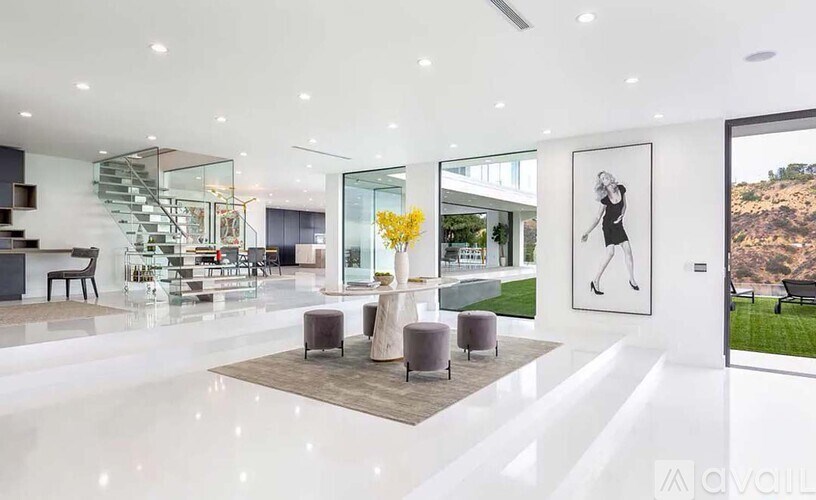 A modern living room with a staircase and a painting of a tennis player.