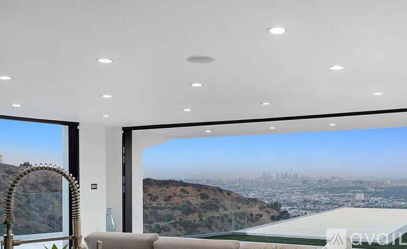 A modern living room with a view of the cityscape outside the large window.