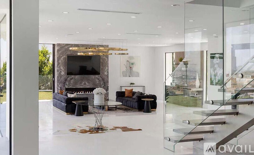 A modern living room with a glass staircase and a fireplace.