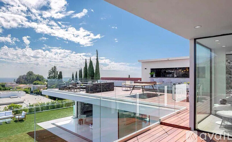 A modern house with a glass wall and a wooden deck.