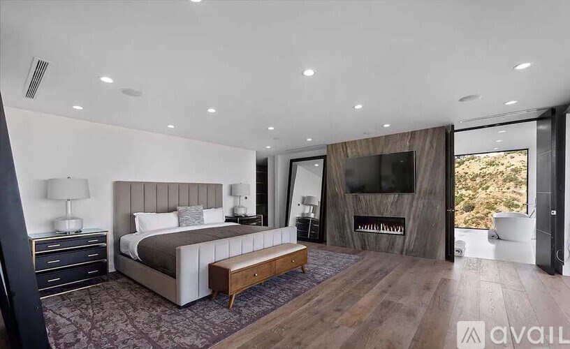 A modern bedroom with a large bed and a television in the background.