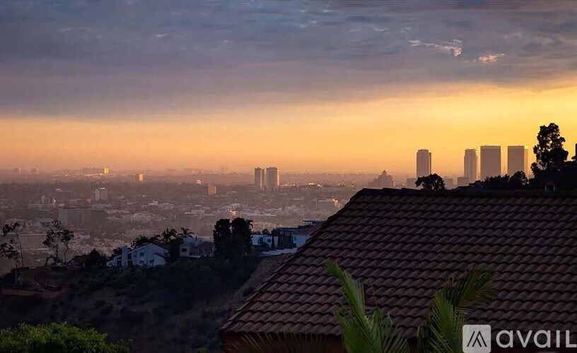 A cityscape at sunset with buildings silhouetted against the sky.