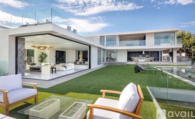 A modern house with a glass table and chairs in the foreground.