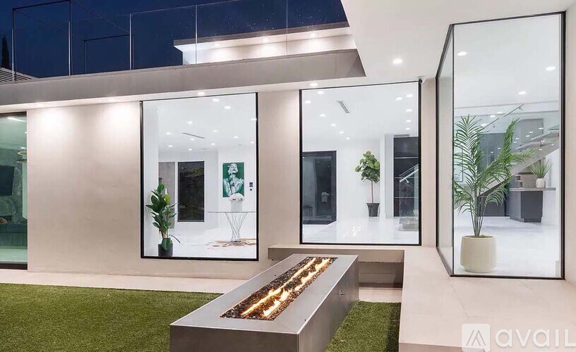 A modern house with a glass wall and a long table in front of it.