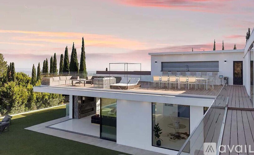 A modern house with a large deck and glass walls.