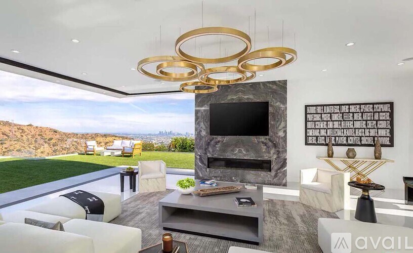 A modern living room with a large flat screen TV and a view of the mountains.
