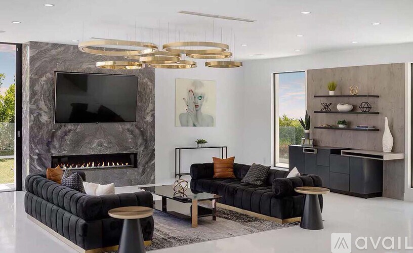A modern living room with a black sofa, a fireplace, and a TV.