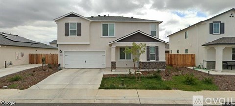 A house with a driveway and a tree in front.