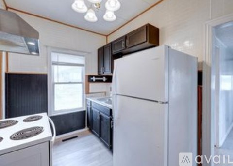 A white refrigerator is in a kitchen with a stove and a microwave above it.