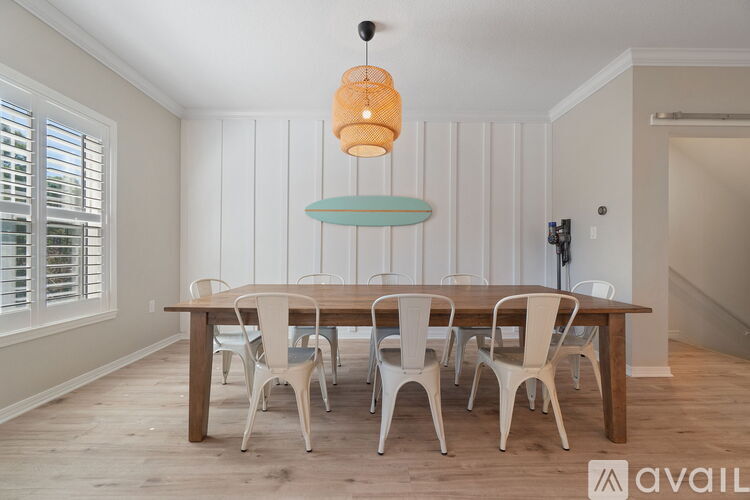 A dining room with a wooden table and white chairs.