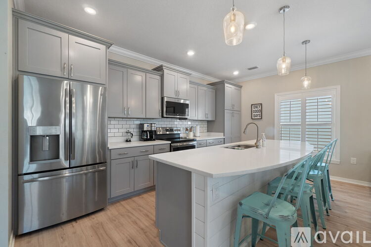 A kitchen with a stainless steel refrigerator and a white island with four chairs.