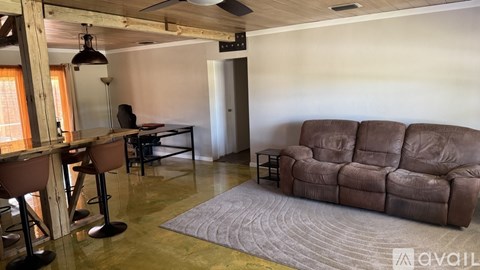 A living room with a brown couch and a bar area.