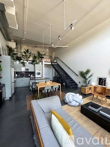 A modern living room with a grey sofa and a kitchen in the background.