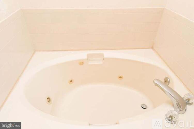 A white bathtub with a silver faucet and a white handle.