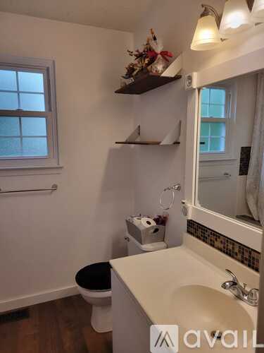 A bathroom with a toilet, sink, and window.