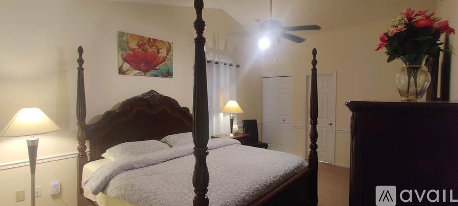 A bedroom with a four poster bed and a painting on the wall.