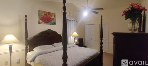 A bedroom with a four poster bed and a painting on the wall.