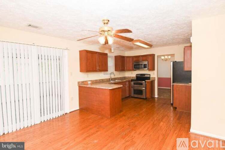 A kitchen with wooden floors and a ceiling fan.
