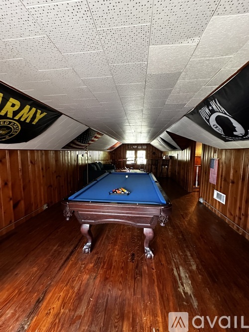 A pool table in a room with wooden floors and a sign that says "ARMY".