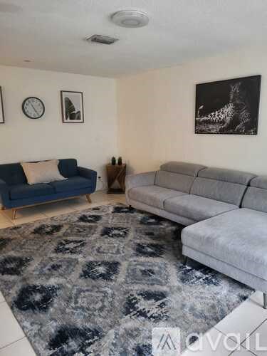 A living room with a grey rug and two couches.