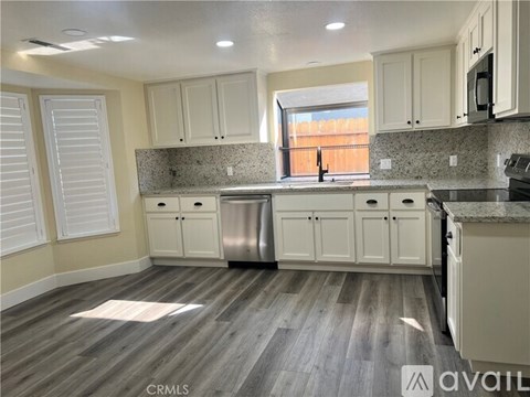 A kitchen with white cabinets and a wooden floor.