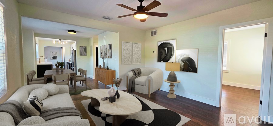 A living room with a white ceiling fan and a black and white rug.