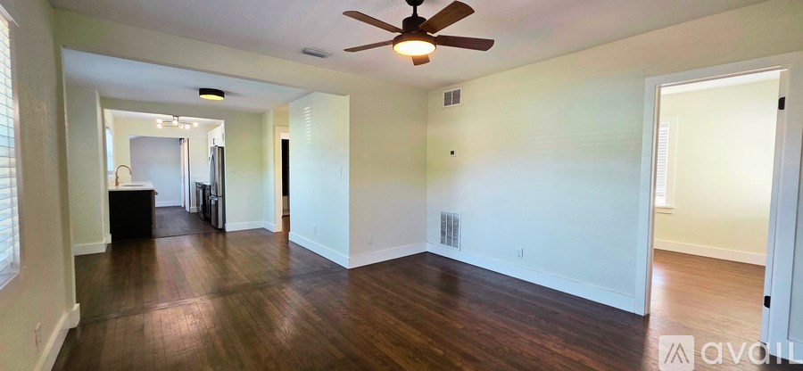 A spacious room with a ceiling fan and hardwood floors.