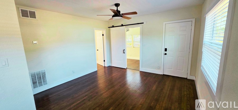 A room with a ceiling fan and wood flooring.