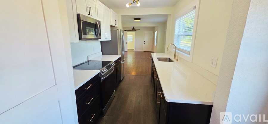A long, narrow kitchen with white cabinets and black drawers.