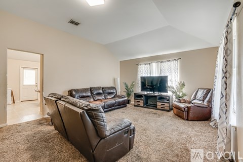A living room with a black leather couch and a television.