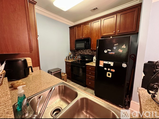 A kitchen with a black fridge and a stove top oven.