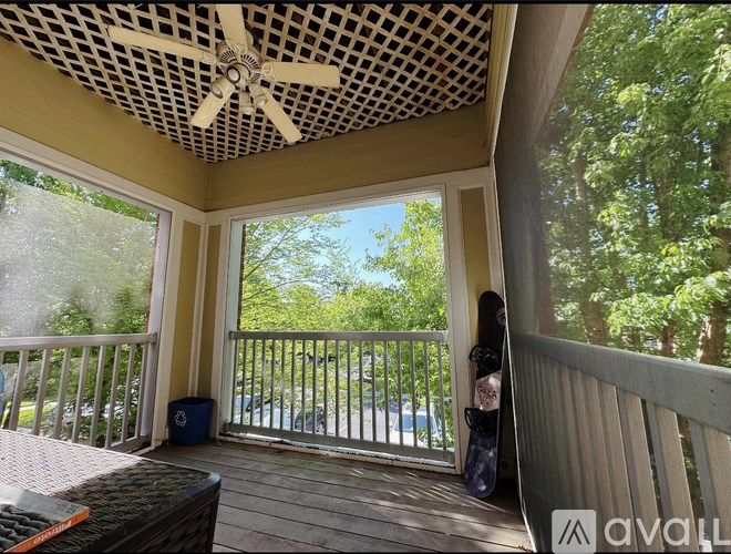 A balcony with a fan and a skateboard leaning against the wall.