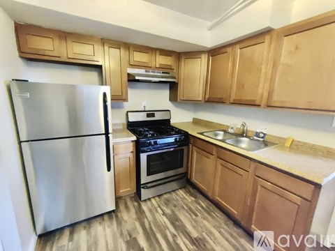 A kitchen with wooden cabinets and a stainless steel refrigerator.