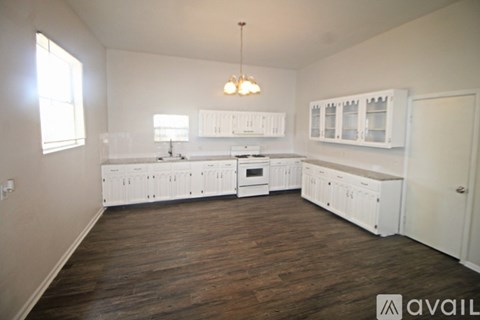 A kitchen with white cabinets and a wooden floor.