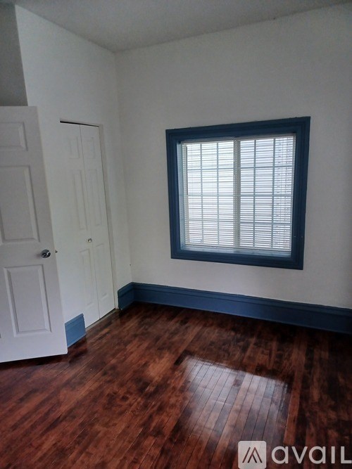 A room with a wooden floor and a window with blinds.