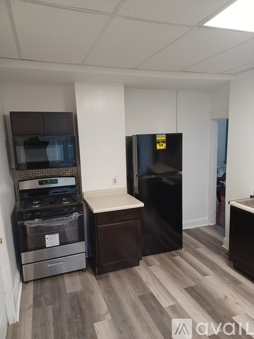 A kitchen area with a black fridge, stove, and microwave.
