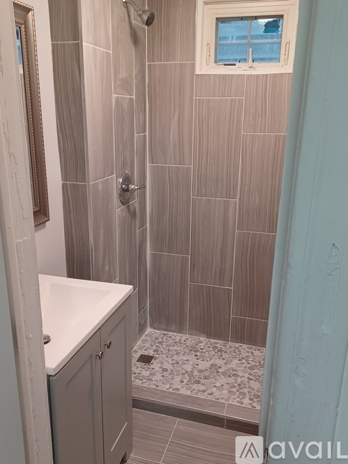 A bathroom with a tiled shower and a window.