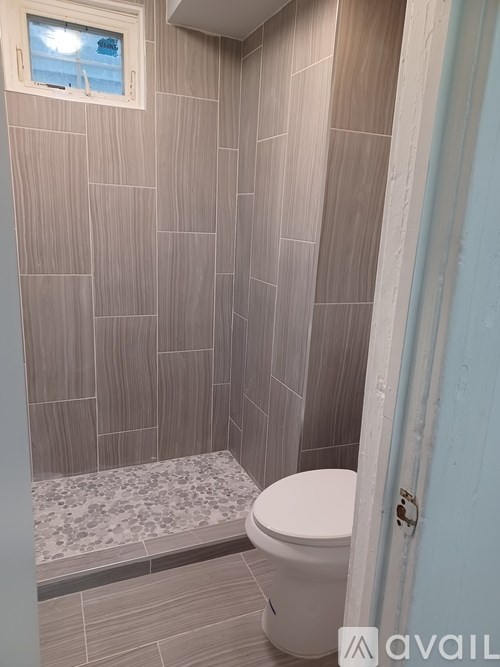A bathroom with a toilet, tiled walls and a window.