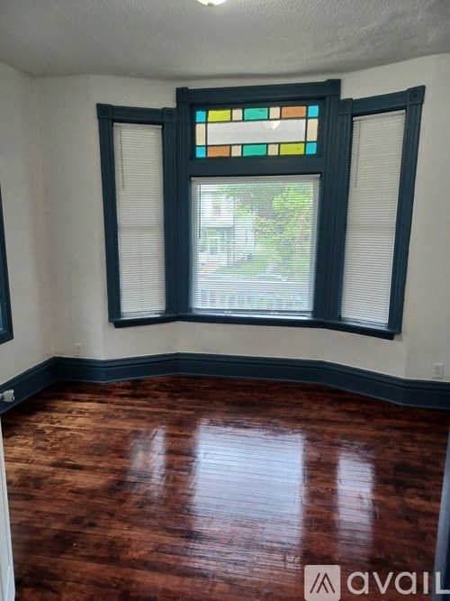 A room with a stained glass window and wooden flooring.