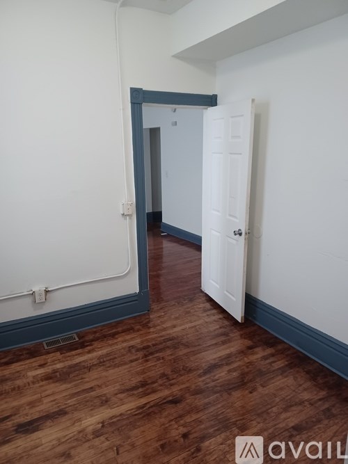 A room with a white door and a wooden floor.