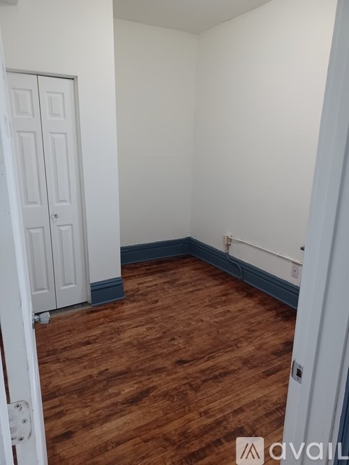 A room with a white door and wooden flooring.