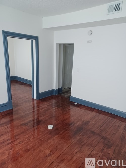 A room with a wooden floor and a white wall with a blue door.