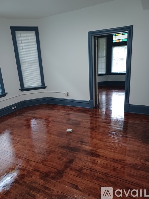 A room with a wooden floor and a door leading to another room.